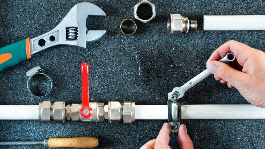 Plumber repairing a pipe valve with an adjustable wrench in Wildwood