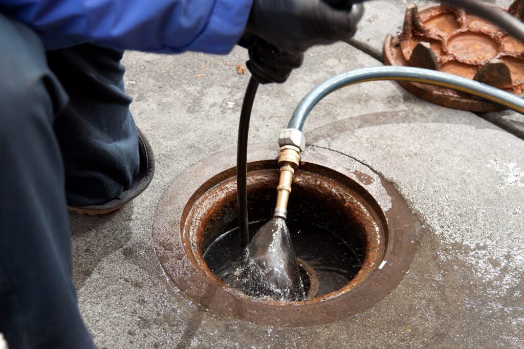 Plumber hydro jetting a sewer line through a manhole in Wildwood