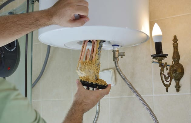 Technician removing mineral buildup from a water heater in Wildwood