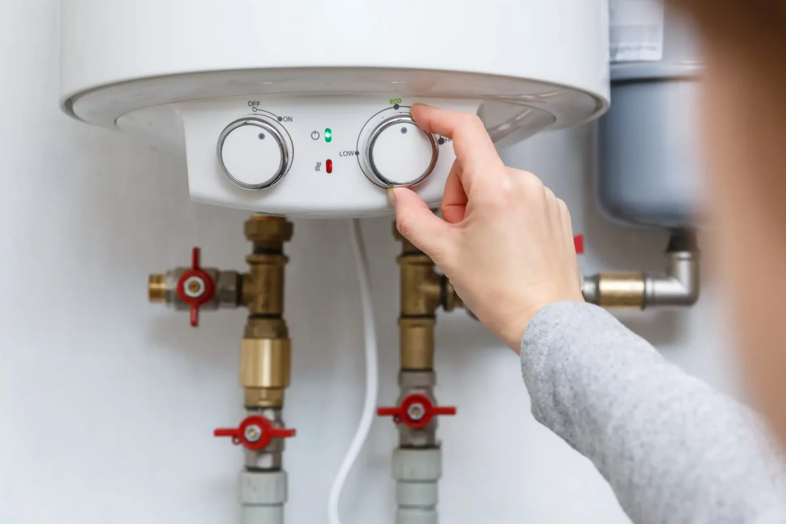 Homeowner adjusting the temperature controls on a water heater in Wildwood